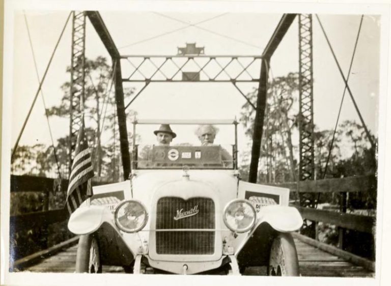 two men driving a car on a bridge, 1915-1916