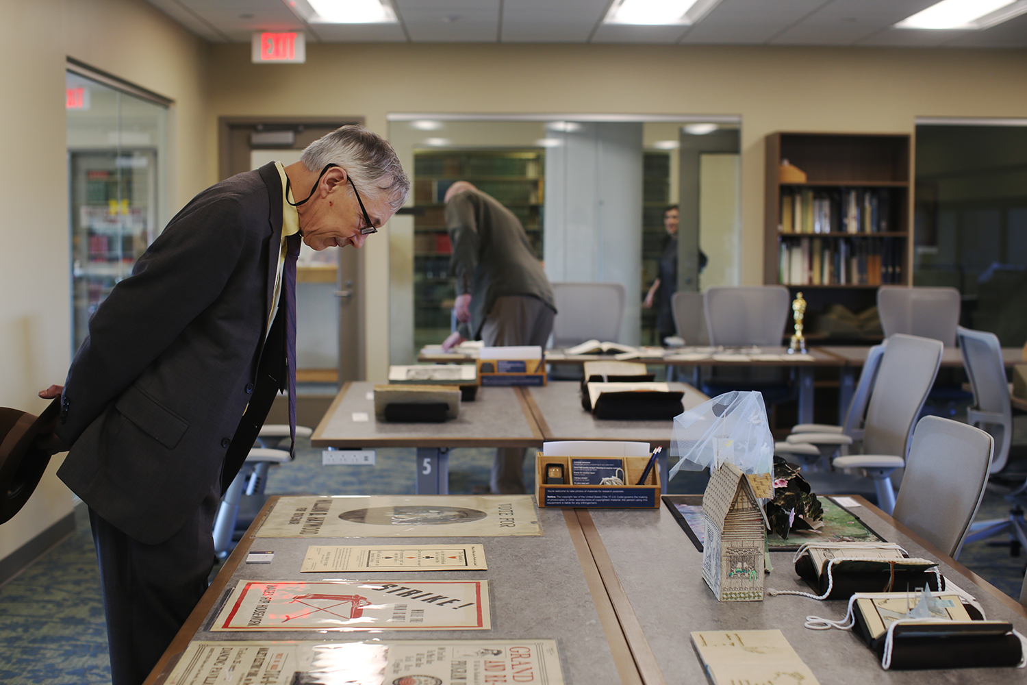 Man viewing posters laid out on a table in the Special Collections Research Center