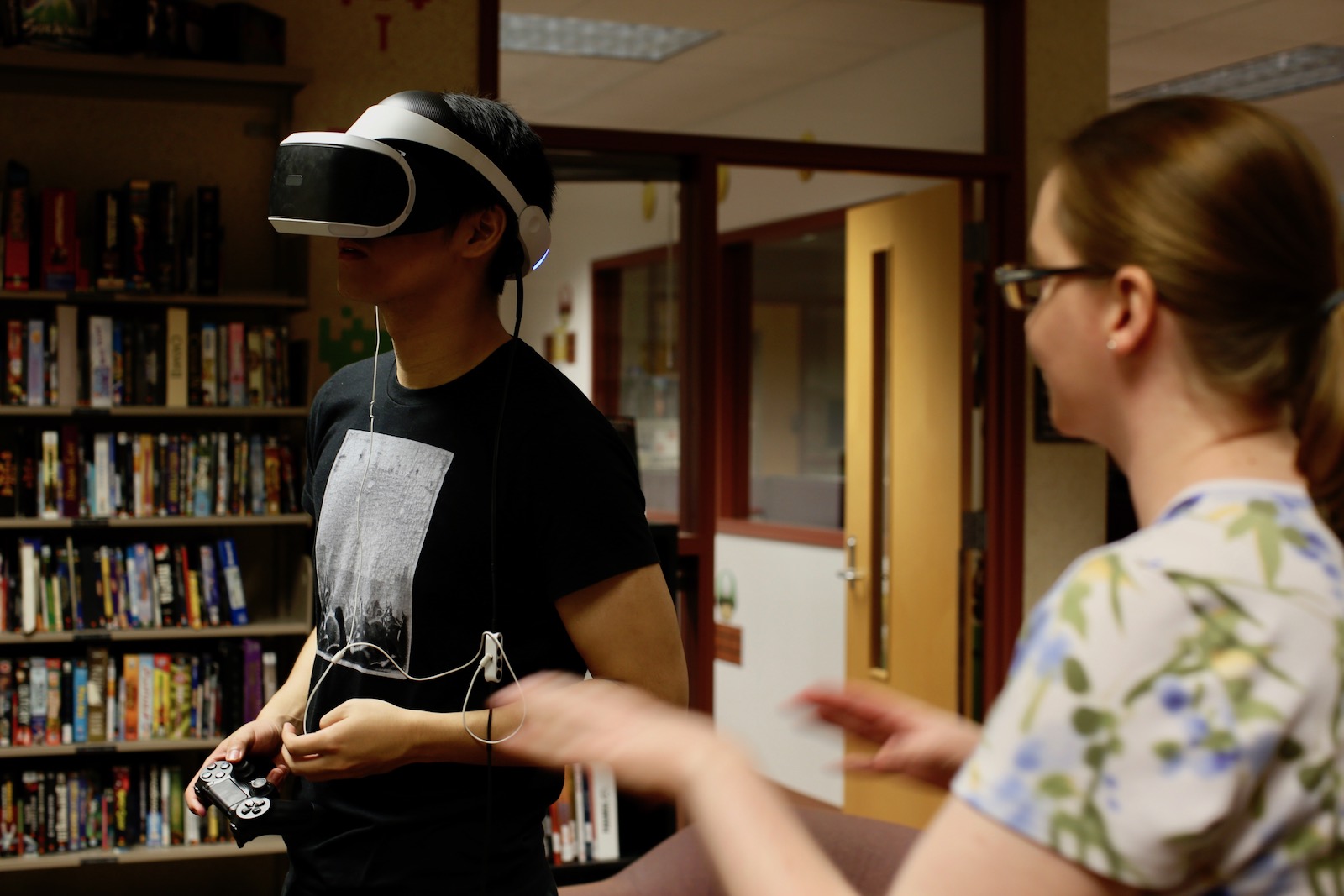 Photo of a man wearing a virtual reality headset with a woman looking on