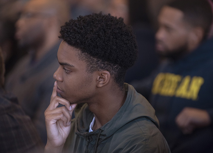 Photo of a man watching a lecture in a crowded audience