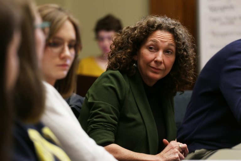 Photograph of a seated woman with students in foreground and background