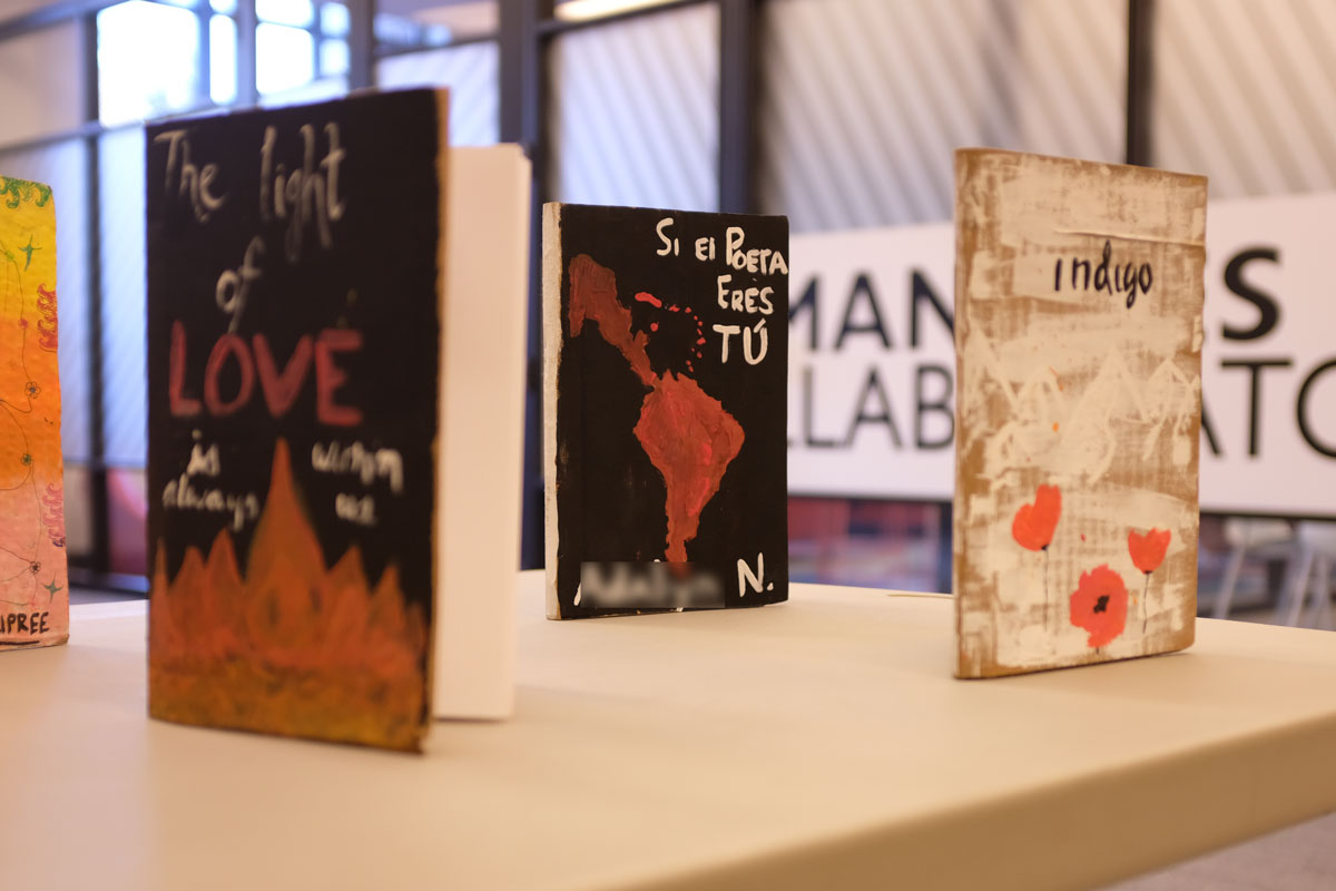 three books standing upright on a table with hand-lettered and illustrated covers